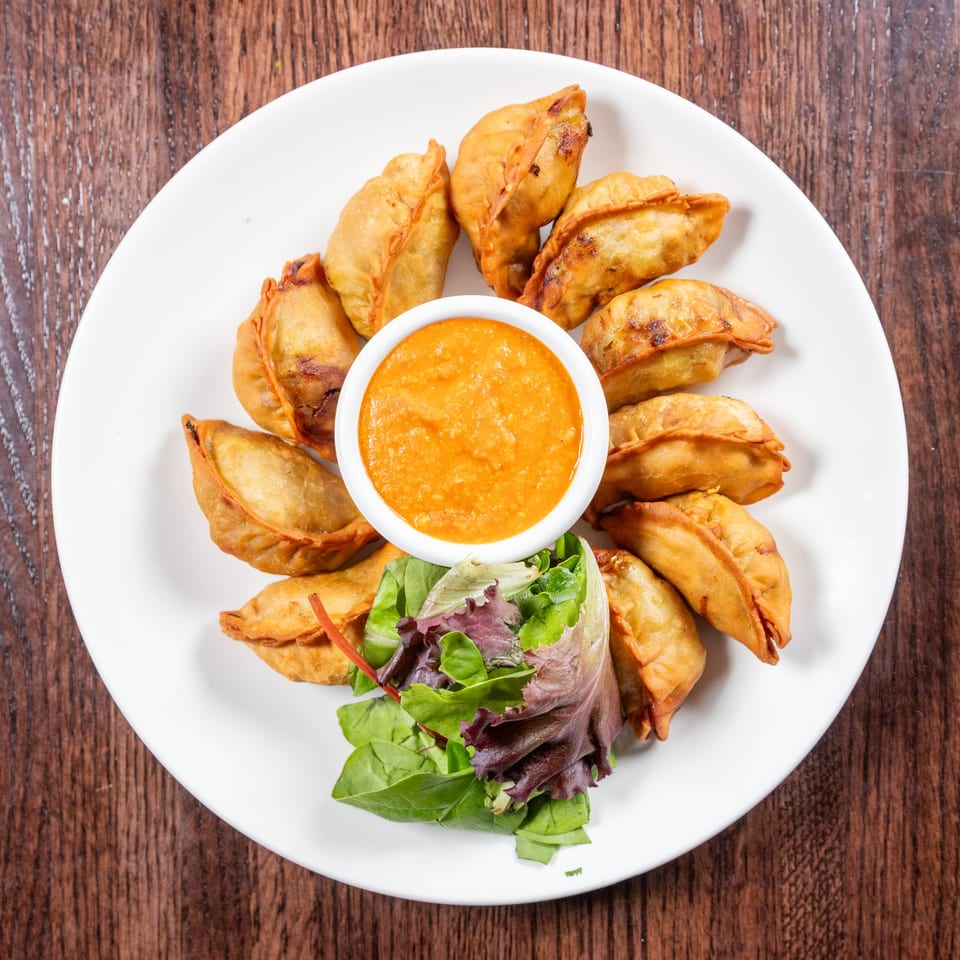 Himalayan Cuisine's fried momos, a Nepalese dumpling dish, with dipping sauce and a side salad.